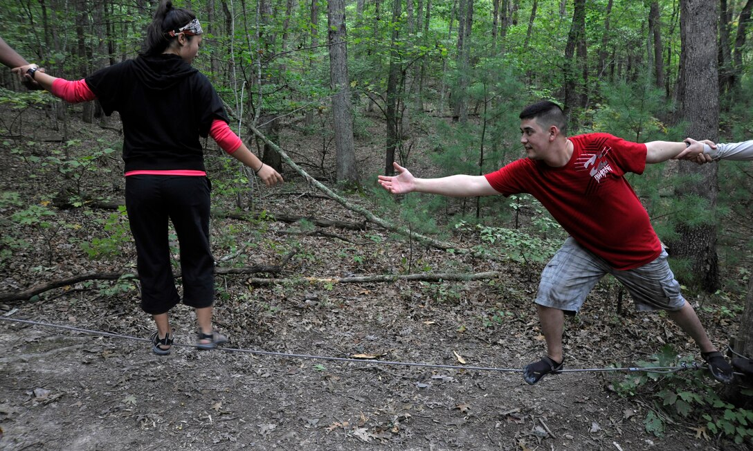 Airman 1st Class William Yano, 744th Communications Squadron cyber transport technician, coaxes Airman 1st Class Stephanie Hunt, 579th Dental Squadron dental assistant, with a helping hand during a low-ropes balance exercise during a JBA Chapel Wilderness Retreat exercise Sept. 22. Yano and Hunt, along with more than 30 other Airmen, built inner confidence and outer enthusiasm while participating in the five-day, all expenses paid retreat. (U.S. Air Force photo/Airman 1st Class Lindsey A. Beadle)