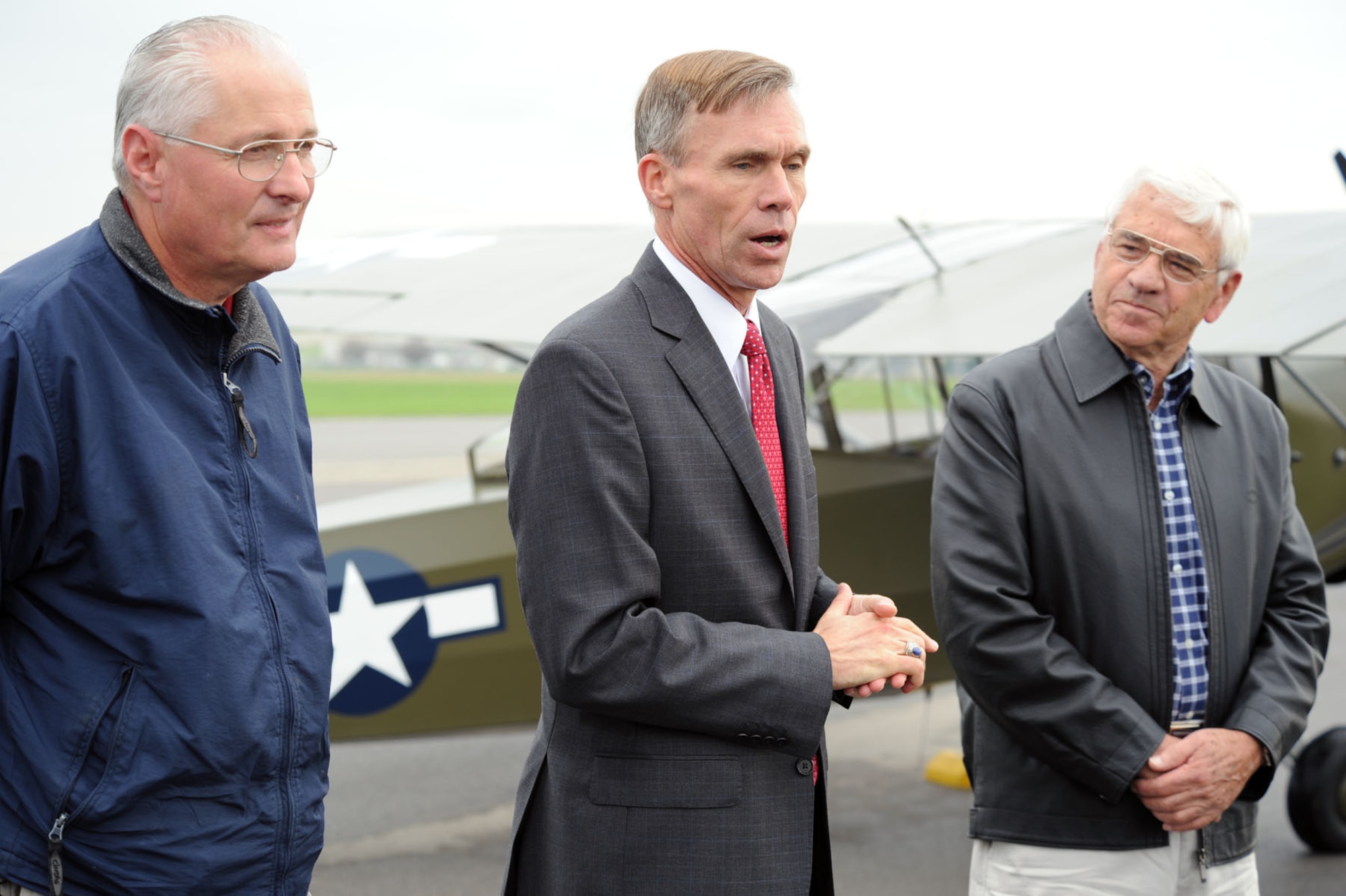 DAYTON, Ohio -- Lt. Gen. (Ret.) John L. "Jack" Hudson (center), director of the National Museum of the U.S. Air Force, addresses the audience after the L-2M made its final flight on Sept. 28, 2011. This L-2M was used at the U.S. Army Air Forces Liaison Pilot Training School during World War II. Also pictured are Dick Valladao (right), the aircraft donor and pilot, and Roger Deere, chief of the museum's Restoration Division. (U.S. Air Force photo by Jeff Fisher)