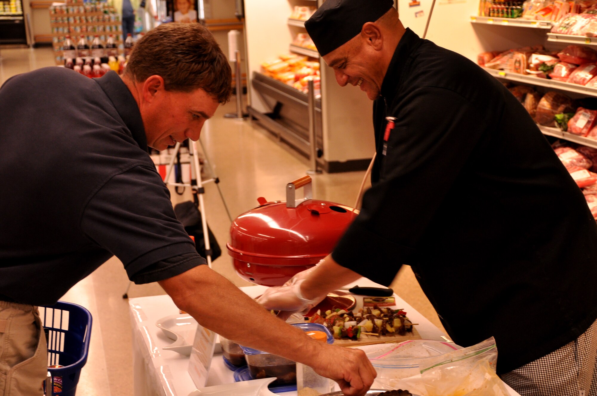 Chef Phil Barfield speaks with a commissary customer while preparing beef shish kebabs Sept. 27 on Grand Forks Air Force Base. The GFAFB Commissary hosted the cooking exhibition in support of DeCA initiative “Go Lean with Protein.” (U.S. Air Force photo/Airman 1st Class Derek VanHorn)