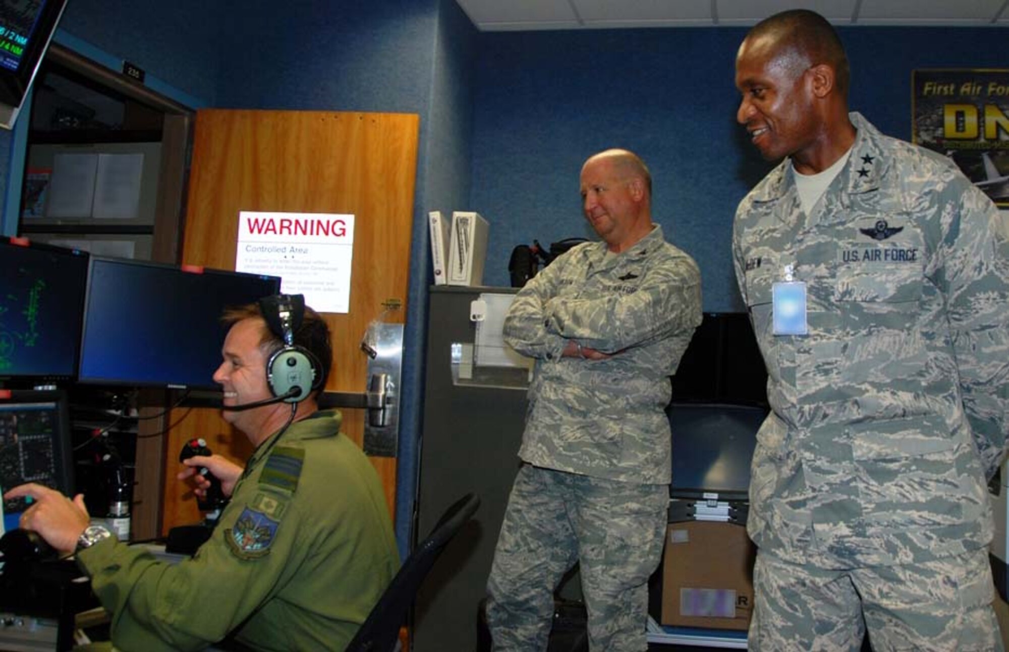 Maj. Gen. Darren W. McDew (right), Air Force District of Washington commander, and Col. Kenneth Carlson (center), also from AFDW, watch as Canadian Air Force Lt. Col. Darron Bazin demonstrates the 601st Air and Space Operations Center’s Distributed Mission Operations system which has the capability to connect people from around the globe into a simulation. McDew visited the 601st AOC and the Killey Center for Homeland Operations during his familiarization tour, receiving mission briefings and watching demonstrations of CONR’s capabilities. (U.S. Air Force photo by Capt. Jared Scott)