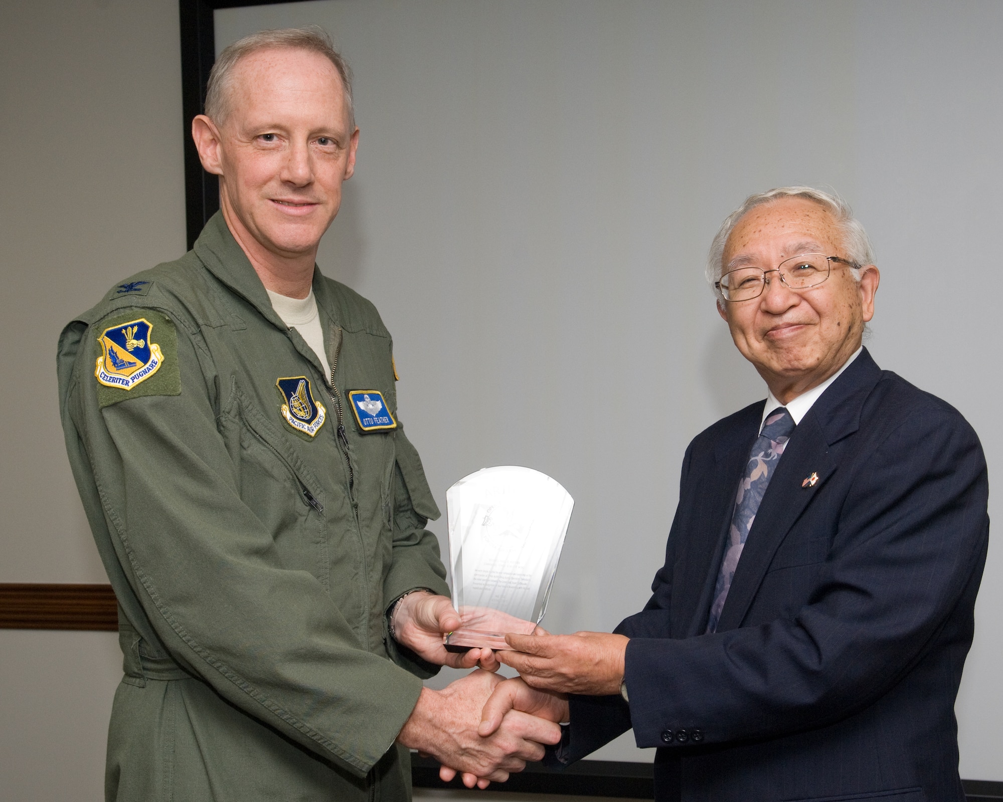 YOKOTA AIR BASE, Japan -- Col. Otto Feather, 374th Airlift Wing commander, accepts an arigato plaque from Hisato Nozawa, president of the Fussa Yokota Goodwill Exchange club, at Yokota Air Base, Japan, 28 Sept. 2011. Members from the Fussa Yokota Goodwill Exchange club presented the plaque to show their appreciation for the support Yokota offered during Operation Tomodachi. (U.S. Air Force photo/Osakabe Yasuo)