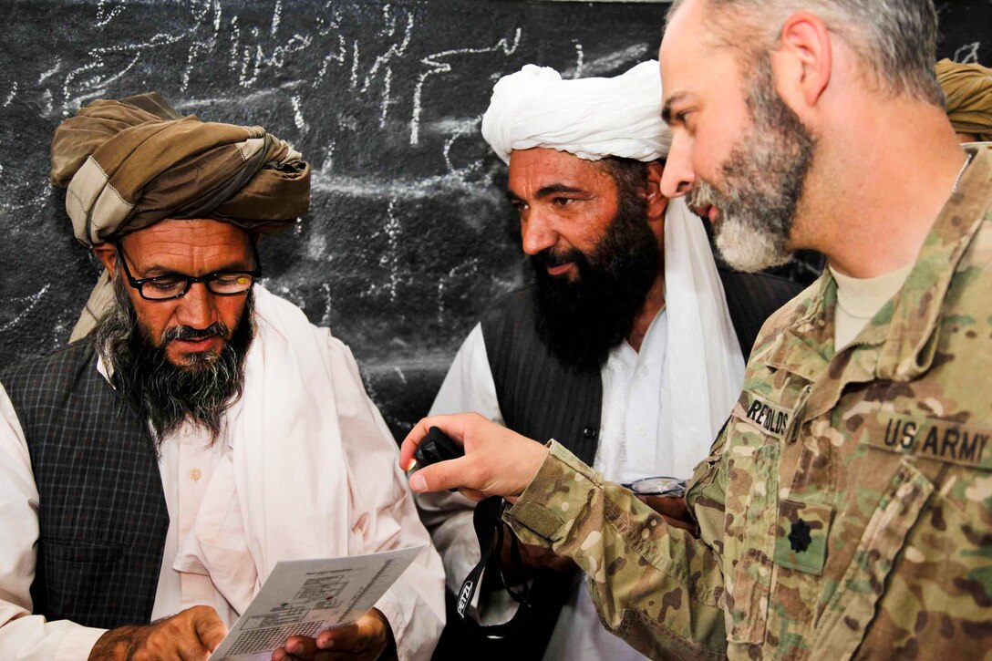 U.S. Army Lt. Col. Mark Reynolds helps test an Afghan man's vision using a visual acuity chart during a village medical outreach program in Herat province, Afghanistan, Sept. 27, 2011. U.S. troops participated in the program, which makes inexpensive glasses available to men, women and school children in the village. 