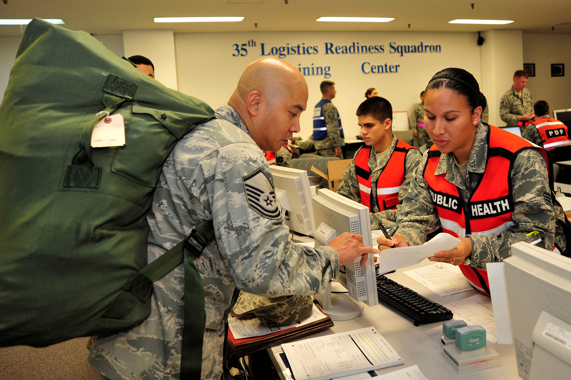 MISAWA AIR BASE, Japan - Master Sgt. Danilo Caraballo, left, 35th Medical Group, makes his way through the personnel deployment function line during an initial readiness response exercise here Sept. 30. The PDF is the final check ensuring all deploying airmen's paperwork and medical records are complete and up-to-date before leaving. (U.S. Air Force photo/Staff Sgt. Nathan Lipscomb)