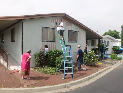 An elderly woman watches as volunteers from the 452nd Air Mobility Wing and 362nd Recruiting Squadron repaint her home during a service project July 16, 2011.  Air Force Sergeant's Association Chapter 1360 organized the project.  The chapter is based at March Air Reserve Base, Calif.  (Courtesy photo)