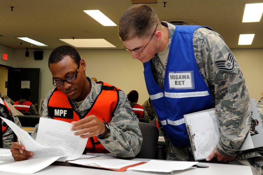 MISAWA AIR BASE, Japan - Senior Airman Deshun Scott, left, 35th Force Support Squadron, reviews a mobility folder as Staff Sgt. Thomas Bazor, exercise evaluation team member, watches over his shoulder at the personnel deployment function here Sept. 29. The 35th Fighter Wing is currently going through an initial readiness response exercise to prepare for an upcoming operational readiness inspection this December. (U.S. Air Force photo/Tech. Sgt. Marie Brown)