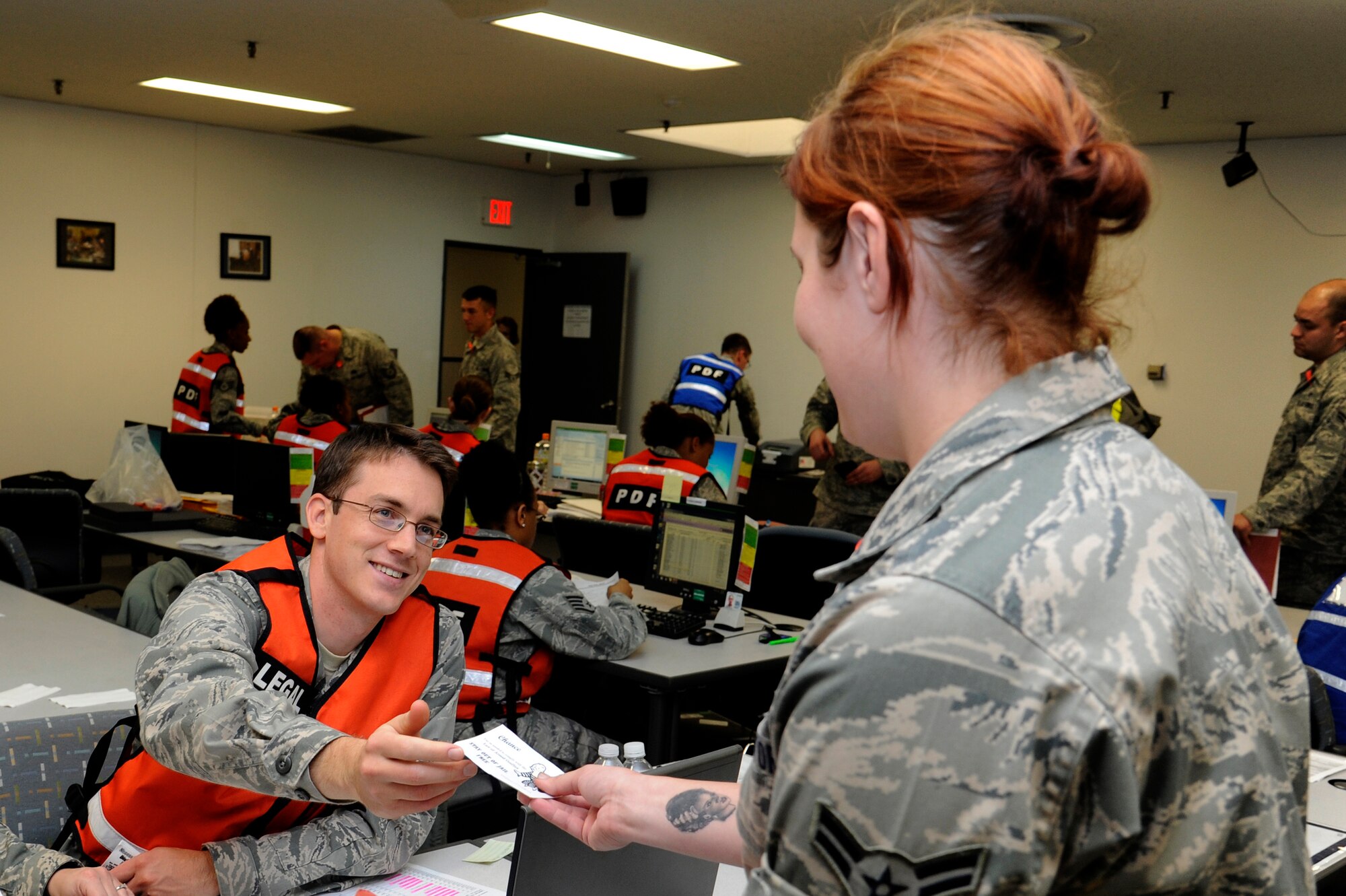 MISAWA AIR BASE, Japan - Capt. Christopher Stein, left, 35th Fighter Wing Judge Advocate Office, hands a law of armed conflict card to a role player while processing through personnel deployment line here Sept. 29. The 35th Fighter Wing is currently going through an initial readiness response exercise to prepare for an upcoming operational readiness inspection this December. (U.S. Air Force photo/Tech. Sgt. Marie Brown)