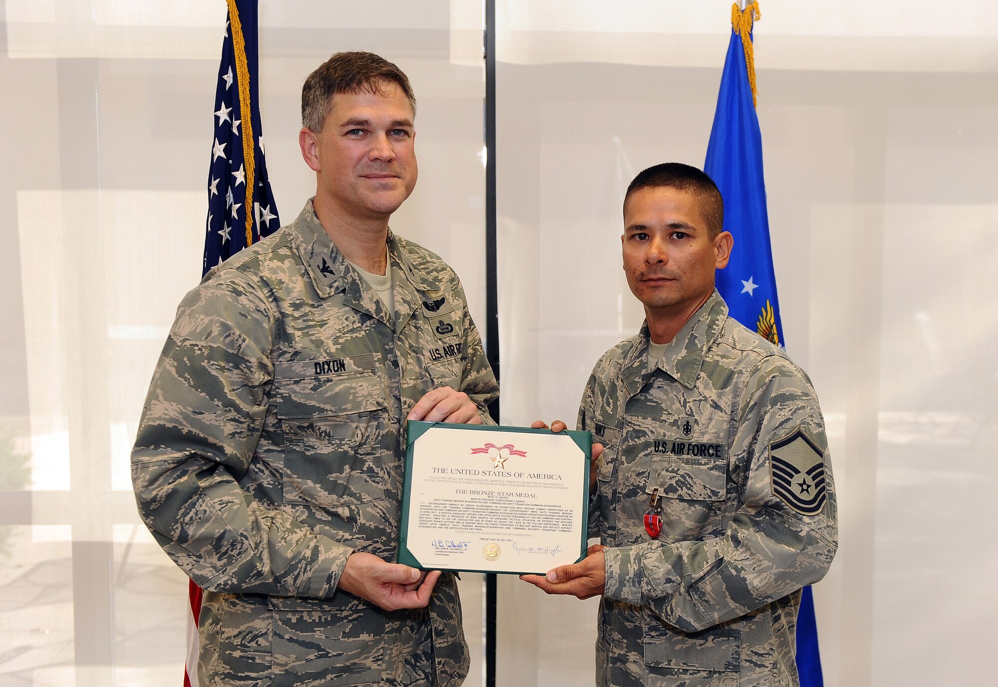U.S. Air Force Col. Kevin D. Dixon, 55th Wing vice commander, presents a Bronze Star certificate to Master Sgt. Christopher Banks at a ceremony held in the 55th Medical Group's dining facility, Offutt Air Force Base, Neb., Sept. 27. Banks earned the medal for his heroic acts performed under extreme real world conditions in Afghanistan.  (U.S. Air Force photo by Josh Plueger/Released).