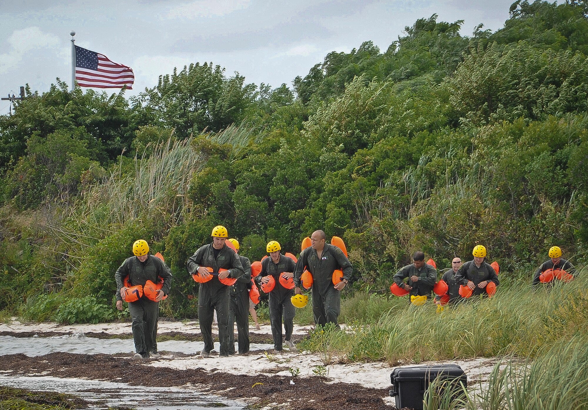 Joint Base McGuire-Dix-Lakehurst air crew members walk the shoreline en route to their next water survival training exercise Aug. 4 at Barnegat Bay, N.J. Coastguardsmen from Coast Guard Air Station Atlantic City, N.J., along with Staff Sgt. Andrew Dunn and Staff Sgt. Timothy Giordana, Joint Base McGuire-Dix-Lakehurst Survival Evasion Resistance and Escape instructors, trained Air Force pilots, crew chiefs and loadmasters on how to survive in the water if ever stranded. An H-65 Dolphin rescue helicopter equipped with a basket hoisted more than 15 Airmen from the water. (U.S. Air Force photo by Airman 1st Class Dennis Sloan/Released)