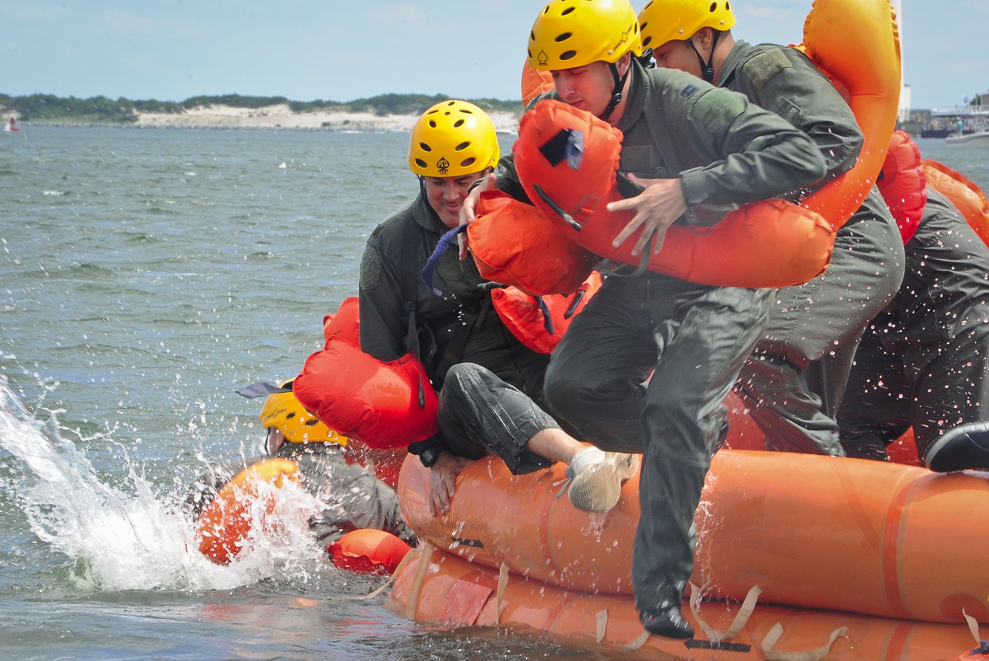 Airmen from Joint Base McGuire-Dix-Lakehurst exit a survival raft by jumping or climbing over the side, during water survival training Aug. 4 at Barnegat Bay, N.J. Coastguardsmen from Coast Guard Air Station Atlantic City, N.J., along with Staff Sgt. Andrew Dunn and Staff Sgt. Timothy Giordana, JB MDL Survival Evasion Resistance and Escape instructors, trained Air Force pilots, crew chiefs and loadmasters on how to survive in the water if ever stranded. More than 15 Airmen were hoisted from the water with the help of a Coast Guard rescue swimmer. (U.S. Air Force photo by Airman 1st Class Dennis Sloan/Released)