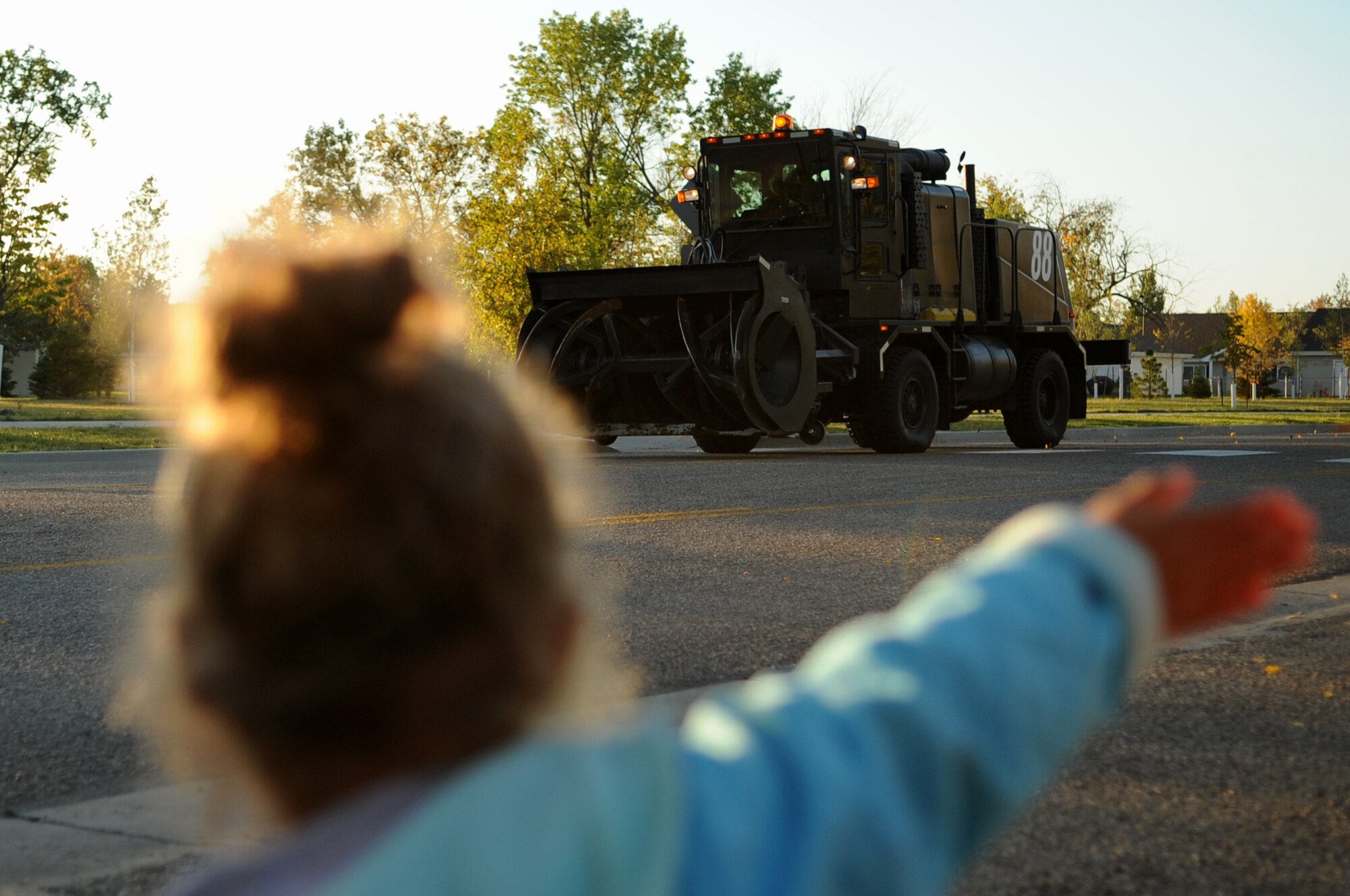 A young girl from the Child Development Center waves during the Snow Removal Equipment Parade on Grand Forks Air Force Base Sept. 29. This year there were 18 snow removal equipment vehicles that participated in the parade which allowed base personnel to see the equipment before the first snow fall. (U.S. Air Force photo by Senior Airman Amanda N. Stencil)