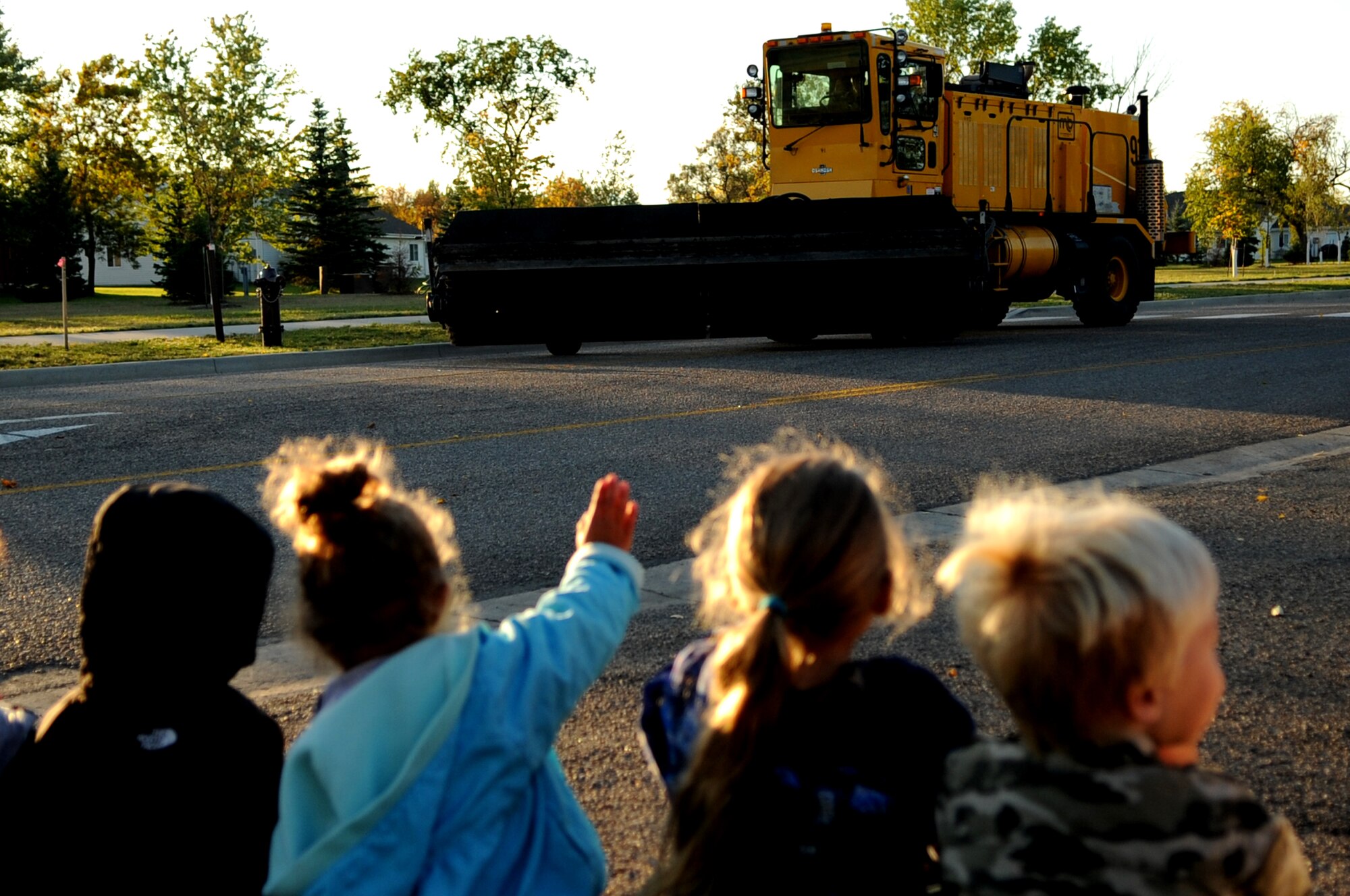 Children from the Child Development Center wave during the Snow Removal Equipment Parade on Grand Forks Air Force Base Sept. 29. This year there were 18 snow removal equipment vehicles that participated in the parade which allowed base personnel to see the equipment before the first snow fall. (U.S. Air Force photo by Senior Airman Amanda N. Stencil)