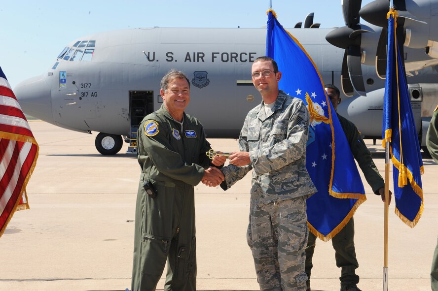 Brig. Gen. Harold Reed, 18th Air Force/Command Guard, presents the honorary key of the newest C-130J to Tech. Sgt. Gordon West, 317th Airlift Group, who is receiving the key on behalf of Staff Sgt Jaime Febus, 317th Airlift Group, who is currently deployed, Sept. 28, 2011, at Dyess Air Force Base, Texas. The aircraft is the eighth of 28 to be delivered to Dyess by 2013, replacing the current aging fleet of the C-130 H model. (U.S. Air Force photo by Airman 1st Class Cierra Bullock/Released)