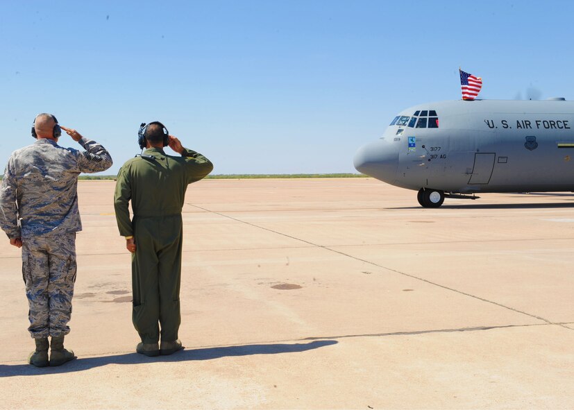 Col. Dan P. Dagher, 317th Airlift Group commander, and Chief Master Sgt. Phillip L. Oliver, 317th Airlift Group superintendent, salute Brig. Gen. Harold Reed, 18th Air Force/Command Guard, as he delivers a new C-130J, Sept. 28, 2011, at Dyess Air Force Base, Texas. The aircraft is the eighth of 28 to be delivered to Dyess by 2013, replacing the current aging fleet of C-130 H model. (U.S. Air Force photo by Airman 1st Class Cierra Bullock/Released)
