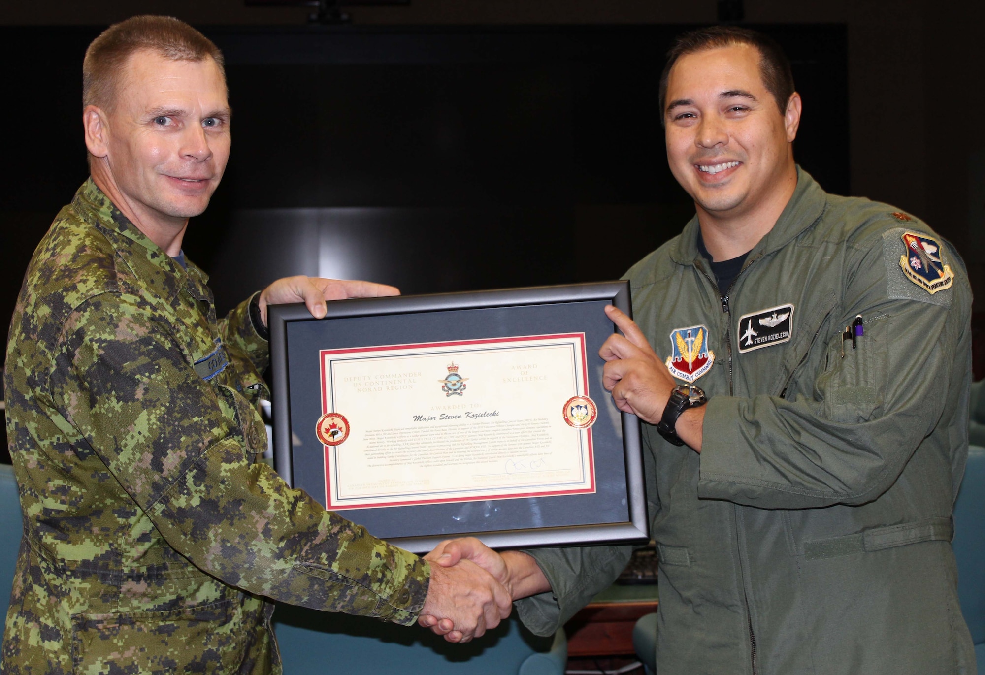 Brig. Gen. Christopher Coates, Continental U.S. North American Aerospace Defense Command Region deputy commander, presents the CONR Deputy Commander Award of Excellence to Maj. Steven Kozielecki, a strategic planner for the 601st Air and Space Operations Center’s Air Refueling Control Team, Sept. 28, marking the first time American military members have received the award. Kozielecki was chosen for the award because of his work during the 2010 Vancouver Winter Olympics and the G20 Toronto Summit. (U.S. Air Force photo by Angela Pope)