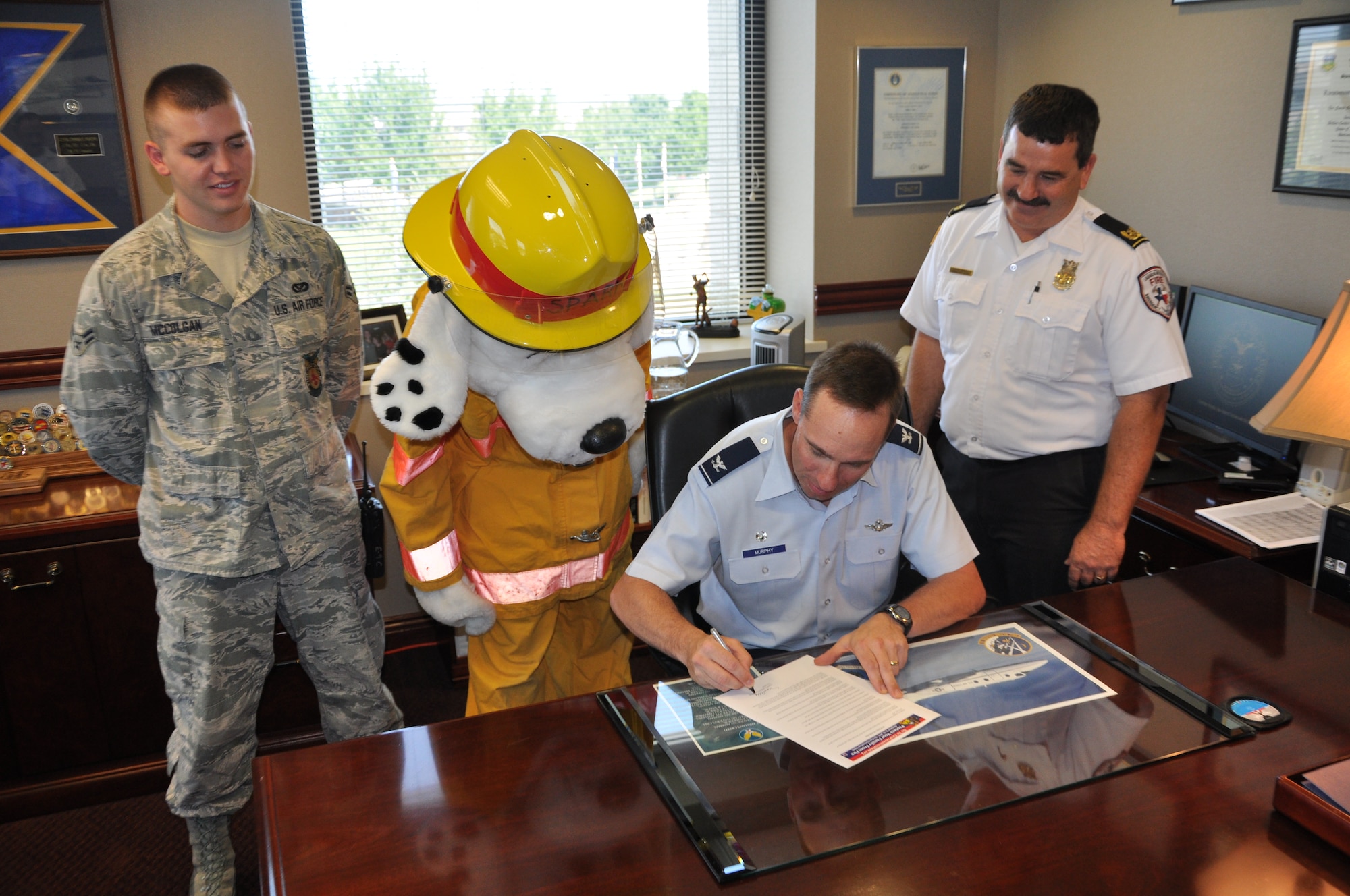 LAUGHLIN AIR FORCE BASE, Texas – Col. Tom Murphy, 47th Flying Training Wing commander, signs a proclamation declaring Oct. 9 through 15 as Fire Prevention Week at Laughlin as David Isbell, Laughlin assistant fire chief, Airman 1st Class Sean McColgan, 47th Civil Engineer Squadron, and Sparky, the fire prevention mascot, look on. (U.S. Air Force photo/Senior Airman Blake Mize)