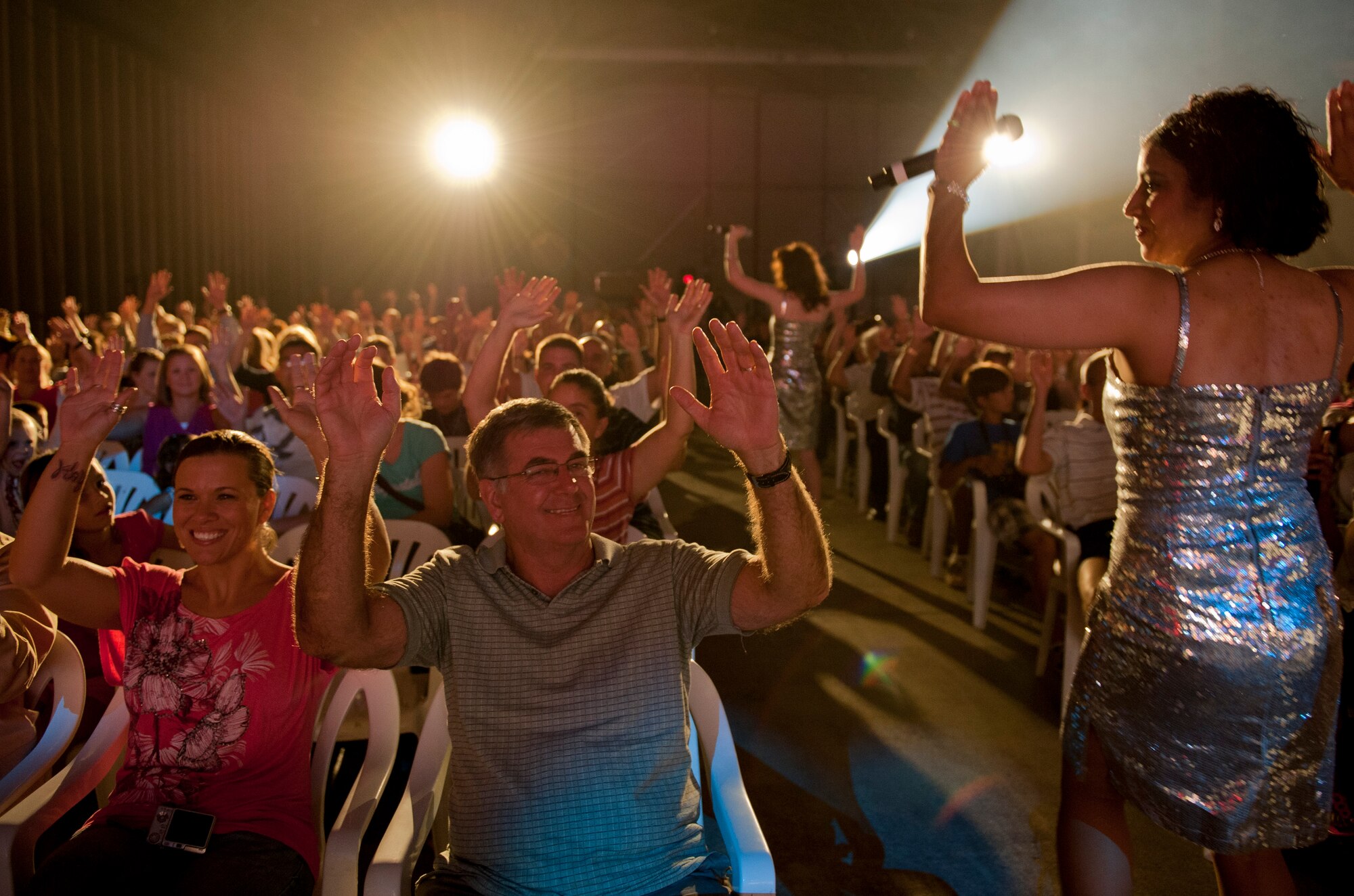 Airmen and families wave their hands in the air during the Tops in Blue performance Sept. 27, 2011, at Incirlik Air Base, Turkey. Tops in Blue is comprised of 35 to 40 vocalists, musicians, dancers and technicians whose primary purpose is to perform for Airmen and their families around the world. (U.S. Air Force photo by Senior Airman Anthony Sanchelli/Released)