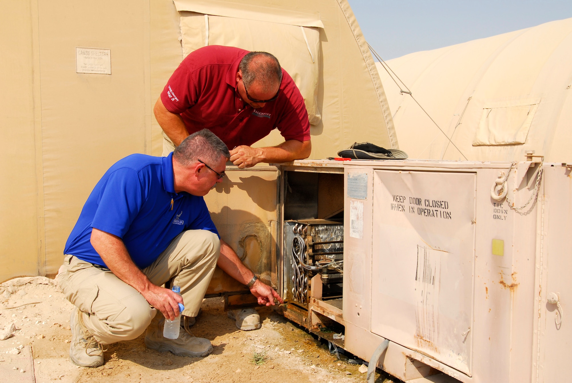 Brian Jarvis, U.S. Air Forces Central Command Energy Manager, along with Robert DeRuyter, 379th Expeditionary Civil Engineering Squadron air conditioning service technician, inspect an environmental control unit used to cool transient personnel tents at an undisclosed location in Southwest Asia on Sept. 29, 2011. Jarvis is exploring the possibility of being able to reduce the number of ECUs by one third simply by making the remaining units run more efficiently. (U.S. Air Force photo by Master Sergeant Gary J. Rihn)