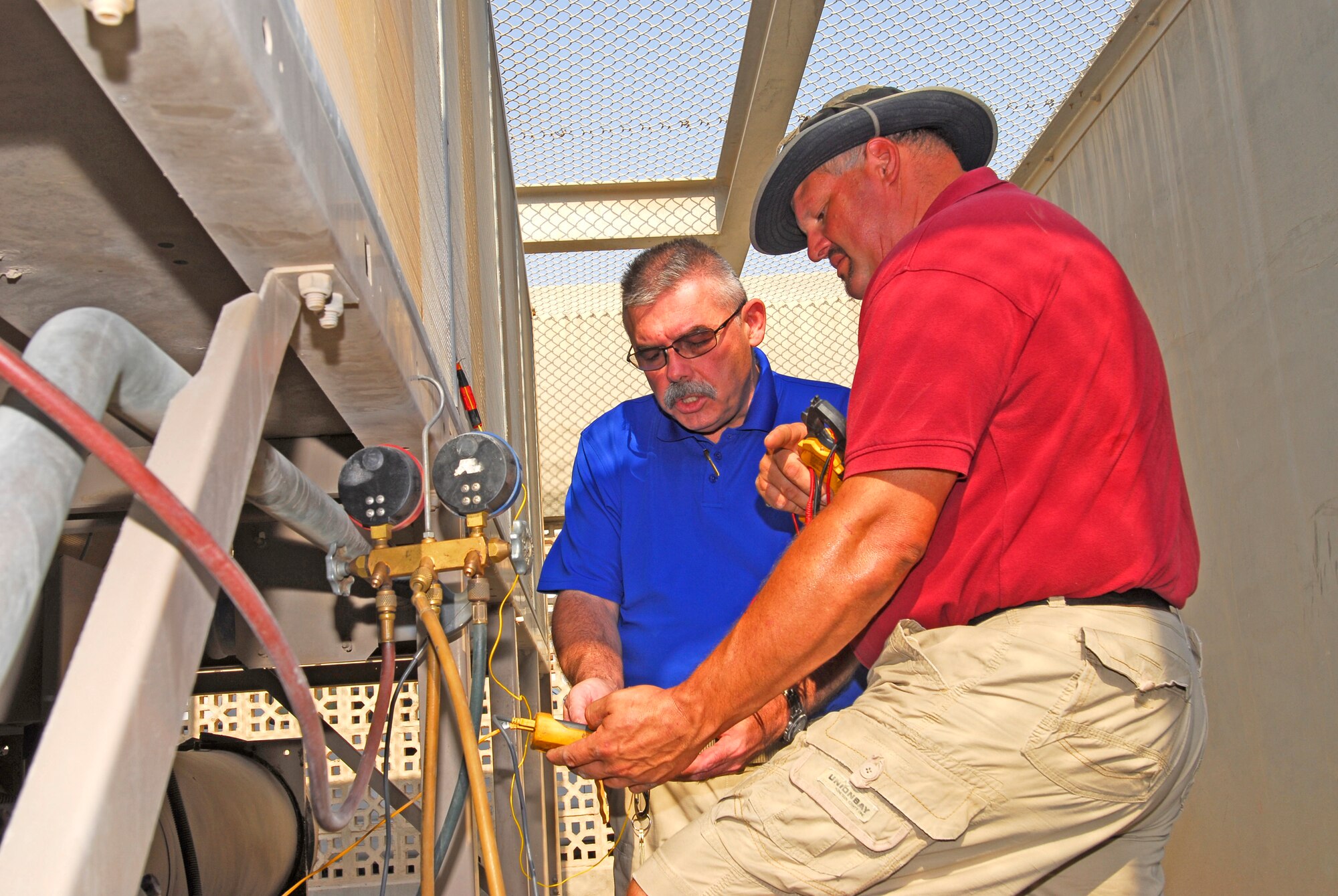 Brian Jarvis, U.S. Air Forces Central Command Energy Manager, along with Robert DeRuyter, 379th Expeditionary Civil Engineering Squadron air conditioning service technician, check instrumentation hooked up to a chiller at an undisclosed location in Southwest Asia on Sept. 29, 2011. Jarvis is trying to determine at what level of use the air conditioning units will run most efficiently. (U.S. Air Force photo by Master Sergeant Gary J. Rihn)