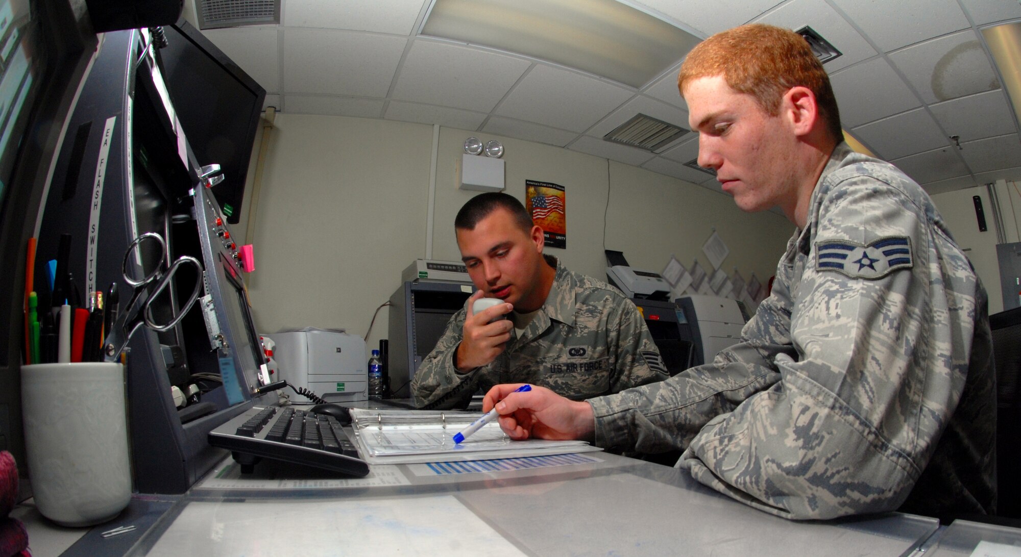 Staff Sgt. Dominick Streeter and Senior Airman Shawn Steele, both 8th Fighter Wing command post controllers, work together as they practice their “Giant Voice” skills at Kunsan Air Base, Republic of Korea, Sept. 28, 2011. The command post is a mission essential office with 12-hour shifts for 24-hour operations. This office, a wing staff agency, is known as the eyes, ears and voice of the wing commander. (U.S. Air Force photo by Senior Airman Benjamin Stratton/Released)