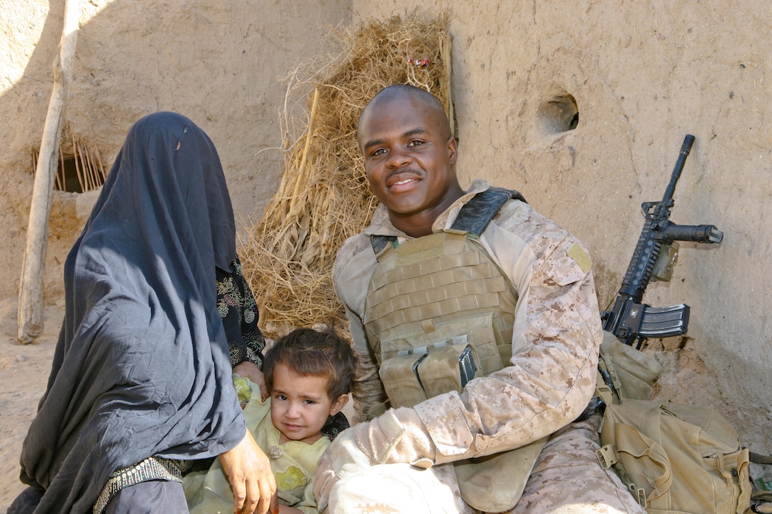 Seaman Apprentice Byron McGill, a Petal, Miss., native and a Navy corpsman with Charlie Company, 1st Battalion, 6th Marine Regiment, takes time for a photo with Basbibi (left), a local resident, and her daughter. The 2-year-old girl drowned in a canal outside her home recently, but McGill revived her and save her life.