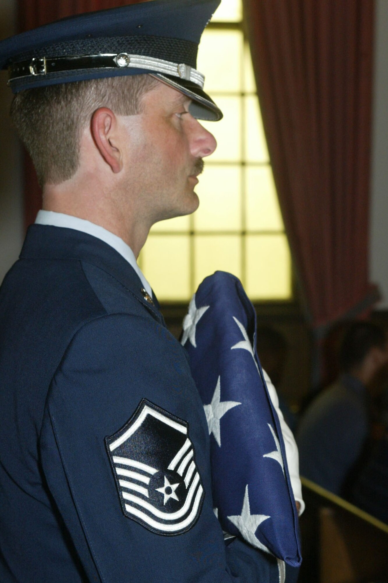 While clasping a folded United States flag, Master Sgt. Bruce See, Honor Guard Superintendant, participates in an honor guard ceremony. Sgt. See is retiring after 20 years of service in the United States Air Force.  From 2005 to 2011, Sgt. See held the title of Honor Guard Superintendant.  (U.S. Air Force photo/ Don Peek)