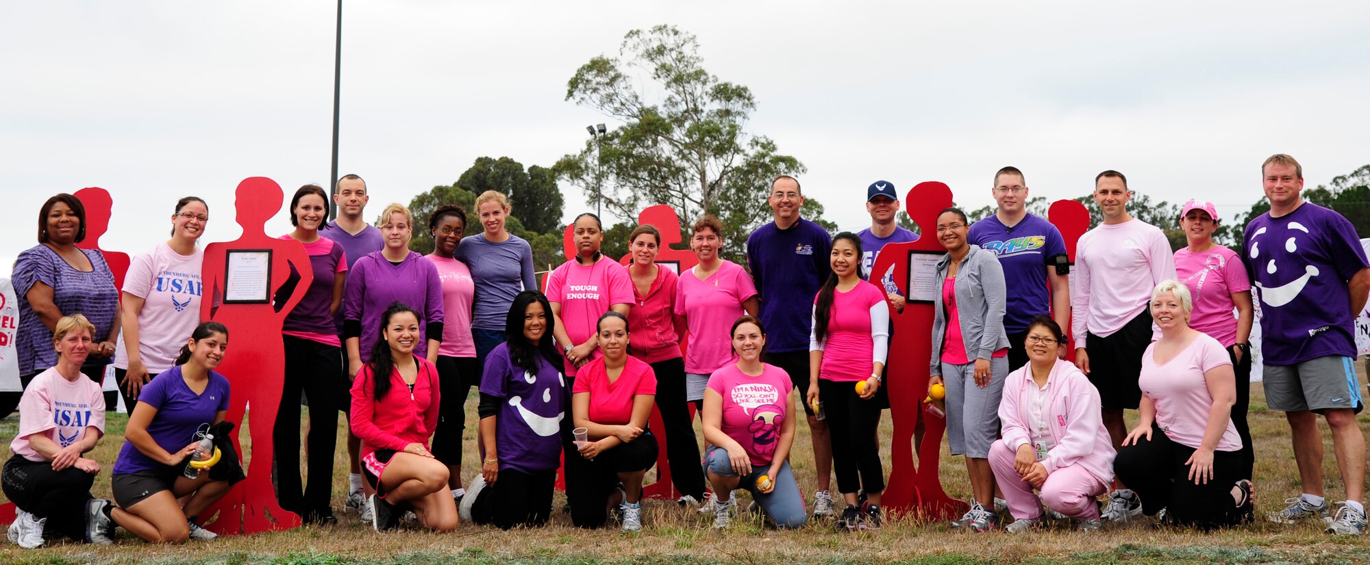 VANDENBERG AIR FORCE BASE, Calif. – Showing off their pink and purple shirts, members of Team V stand together in front of the Clothesline Project after the wing run here Friday, Sept. 30, 2011. The Clothesline Project was made of shirts that were designed by women affected by domestic violence.  (U.S. Air Force photo/Senior Airman Lael Huss)