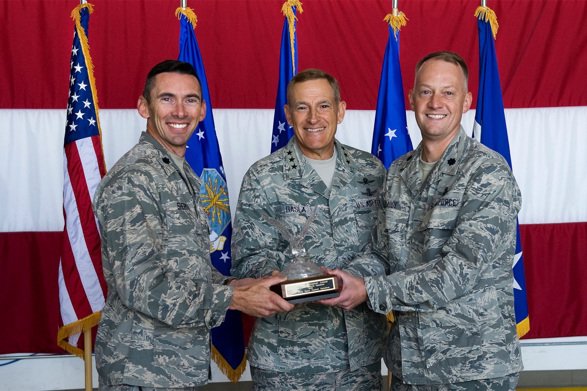 PETERSON AIR FORCE BASE, Colo. -- Lt. Cols. Roger Sherman (left), 16th Space Control Squadron commander, and Bob Claude (right), 380th SPCS commander, accept the Chief Master Sergeant Robert G.V. Pecqueur Award Sept. 21 from Lt. Gen. Michael Basla (center), Air Force Space Command vice commander. The award recognizes the best space control squadron in Air Force Space Command. Airmen from the two squadrons deployed for a total of 3,285 days in direct support of Operations Enduring Freedom, Iraqi Freedom, and New Dawn, providing critical defensive space control ability to U.S. Central Command, and protected more than 300 high priority satellite communications links and thousands of remotely piloted aircraft missions from interference, directly impacting combat operations in the theater. (U.S. Air Force photo/Craig Denton)