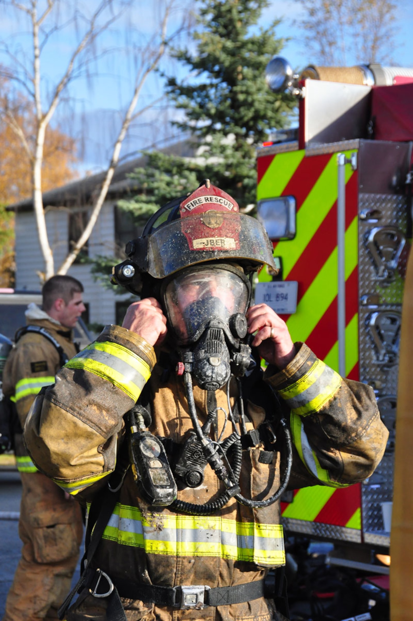 JBER firefighter Airman 1st Class Andrew Morris removes his  self-contained breathing apparatus after emerging from a house fire, Wednesday. (U.S. Air Force photo/Maj. Joseph Coslett)