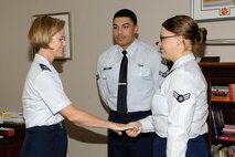 Col. Stacy Yike, 66th Air Base Group commander, presents Airman 1st Class Samantha McInnis a commander's coin Sept. 26, while Airman 1st Class Erik Correa, who also received a coin, looks on. Both Airmen were key members of a team that worked to replace old analog phones with new Voice Over Internet Protocol (VoIP) phones.  By helping replace more than 1,200 phones in seven buildings, they helped save the base $475,000 annually.  (U.S. Air Force photo by Linda LaBonte-Britt)