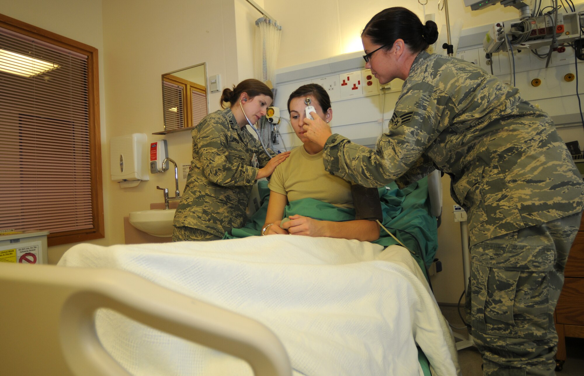 ROYAL AIR FORCE LAKENHEATH, England - Capt. Mary Pride(left), 48th Inpatient Care Squadron Multi-Service Unit clinical nurse, checks a patient's pulse while Senior Airman Krystle Clark, 48th IPTS SGIA Multi-Service Unit medical technician, checks her temperature on Sept 26, 2011.  The MSU provides care to post operation patients and direct admissions from various clinics and the emergency room. (U.S. Air Force photo by Airman Cory D. Payne)