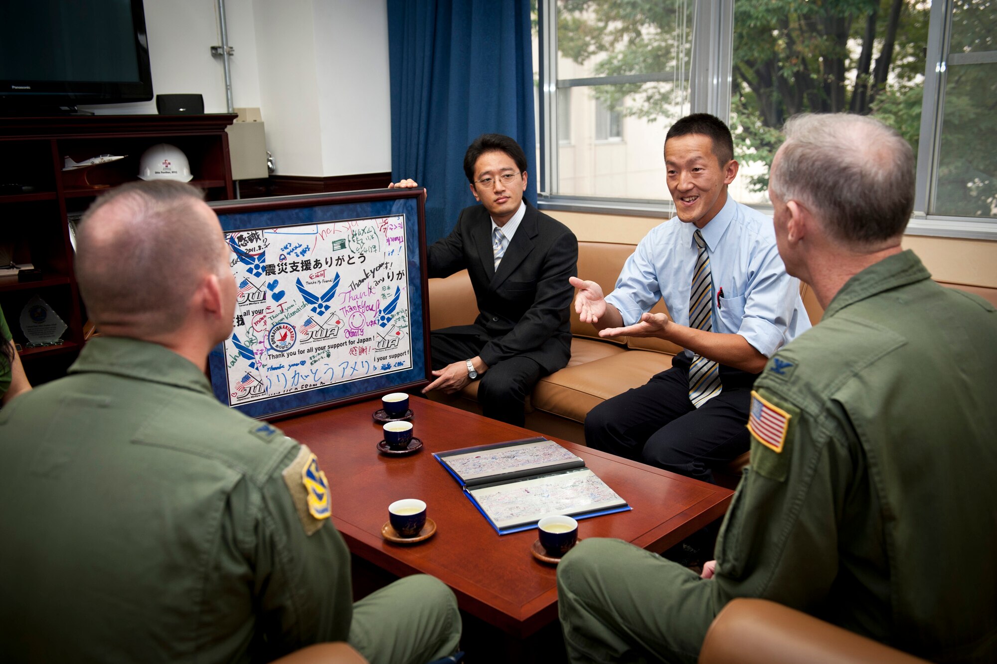 YOKOTA AIR BASE, Japan -- Members of the Japan Welfare Association present a framed signature board to Col. Otto Feather (right), 374th Airlift Wing commander, and Col. Bill Knight (left), 374th AW vice commander, at Yokota Air Base, Japan, Sept. 30, 2011, in appreciation for the wing's efforts during Operation Tomodachi. Japanese guests at the 2011 Friendship Festival signed every available space of several sheets of paper, which were then folded into the frame. Each individual sheet was photographed and placed into an album so each "thank-you" could be read. This board is one of many tokens of appreciation the wing has received during what has come to be known as "Operation Arigato." (U.S. Air Force photo/Staff Sgt. Samuel Morse)