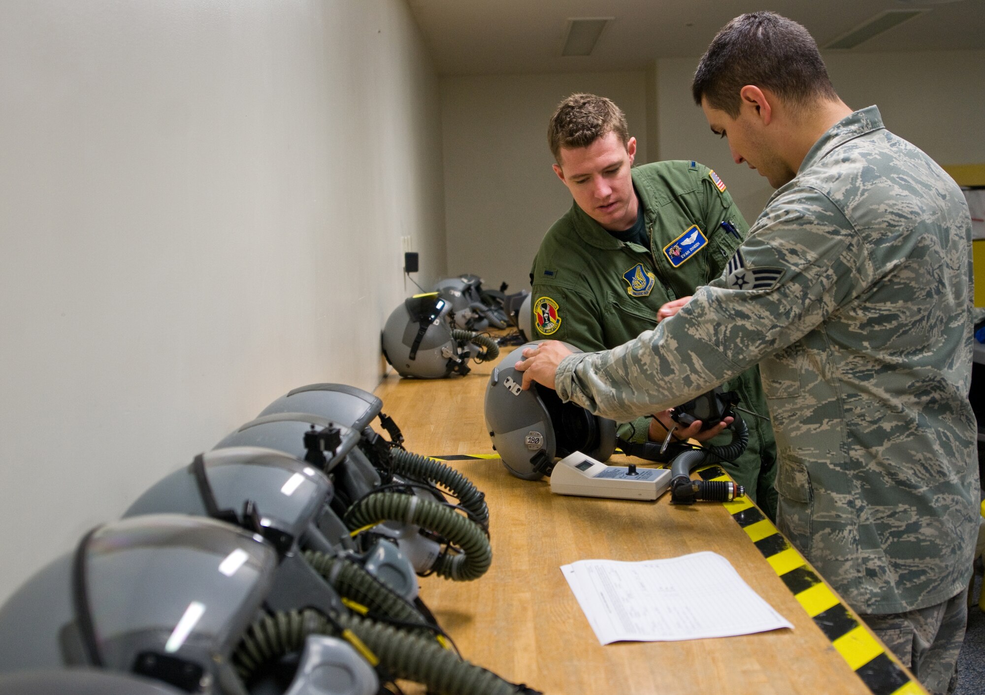 YOKOTA AIR BASE, Japan -- Senior Airman Christopher Sanchez, 374th Operations Support Squadron, assists 1st Lt. Evan Dineen, 36th Airlift Squadron pilot, with his HGU-55P flight helmet at Yokota Air Base, Japan, Sept. 27, 2011. The HGU-55P helmet is required for all tactical missions and offers safety and communication support for flight crew members. (U.S. Air Force photo/Airman 1st Class Krystal M. Garrett)