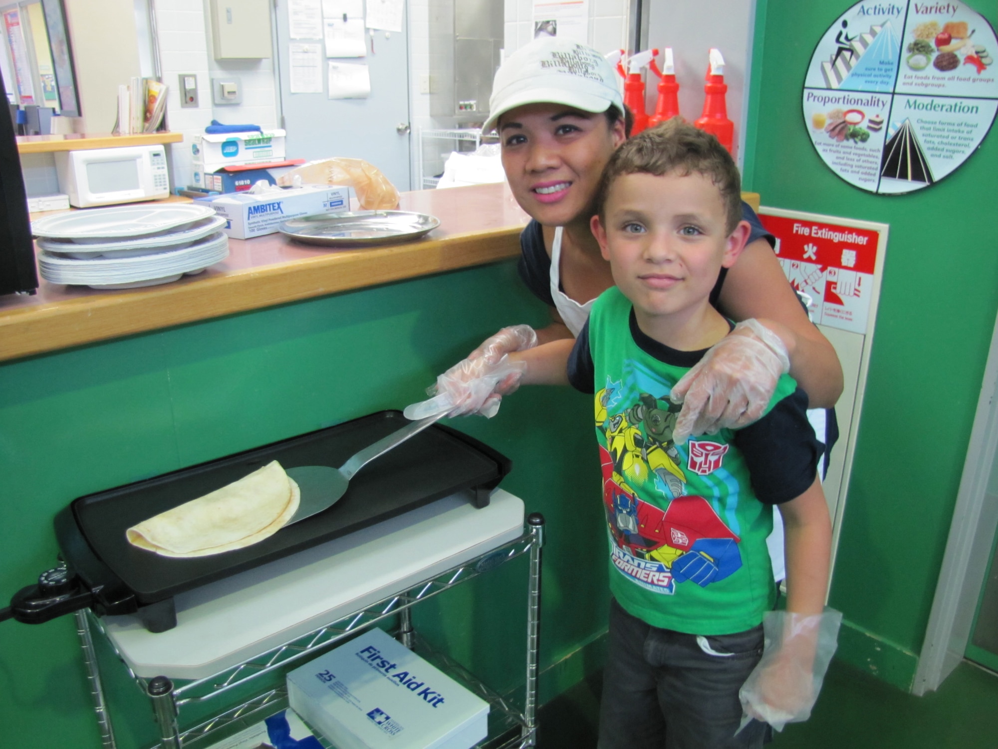 YOKOTA AIR BASE, Japan -- Mildred Halili cooks with a child at the School Age Program June 24, 2011, at Yokota Air Base, Japan. Halili recently won the 2011 Pacific Air Forces' Top Kitchen award and received $3,000 for kitchen equipment along with other prizes. (Courtesy photo)