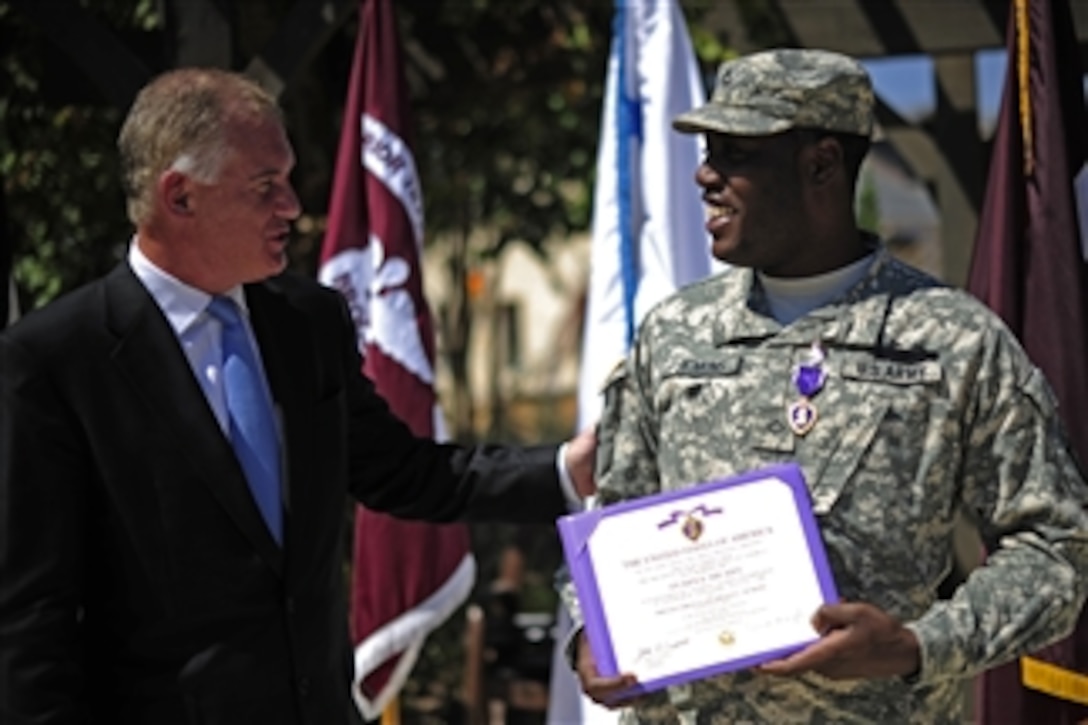 Deputy Secretary of Defense William J. Lynn III congratulates Pfc. Milton Jenkins after presenting him the Purple Heart during a ceremony at the Warrior Family Support Center, Brooke Army Medical Center, San Antonio, Texas, on Sept. 28, 2011.  