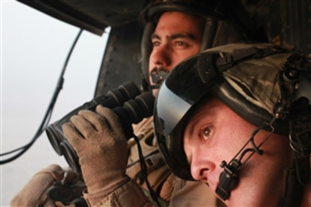 U. S. Marine Corps Sgt. Arturo Fernandez, left, and Gunnery Sgt. Russell J. Hufsey look to the horizon from their UH-1Y Huey while providing close-air support for ground forces in southwestern Afghanistan, on Sept. 15, 2011.  Both Marines are crew chiefs with Marine Light Attack Helicopter Squadron 267.  