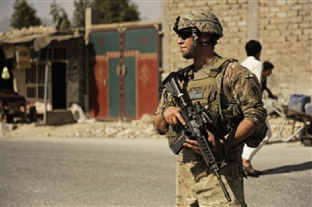 U.S. Army Spc. Alexander Oliveira provides security at an intersection while Afghan Uniformed Police lead the way on a joint patrol in Mehtar Lam district, Laghman Province, Afghanistan, on Sept. 26.  The Police Transition Assistance Team attached to the Laghman Provincial Reconstruction Team is responsible for the training and mentorship of the local Afghan police and routinely conducts joint training with them.  
