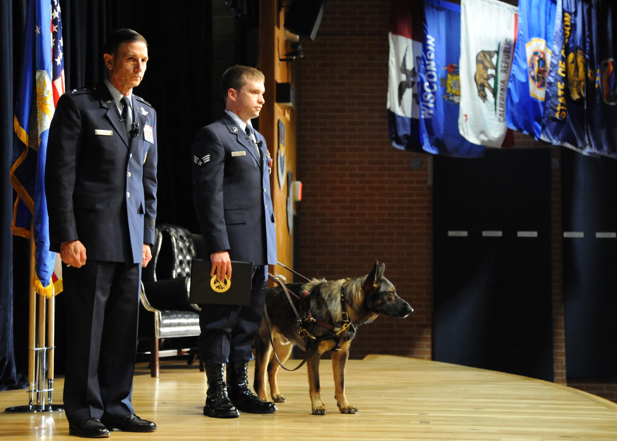 Senior Airman Michael Malarsie and his seeing-eye dog, Xxon, prepare to leave the stage with Maj. Gen. Byron Hepburn, 59th Medical Wing commander, March 30, 2012 at Wilford Hall Ambulatory Surgical Center, Lackland Air Force Base, Texas. Malarsie received the Bronze Star with Valor for heroism as a Tactical Air Control Party Member while deployed to Afghanistan. (U.S. Air Force photo/Senior Airman Kevin Iinuma)  
