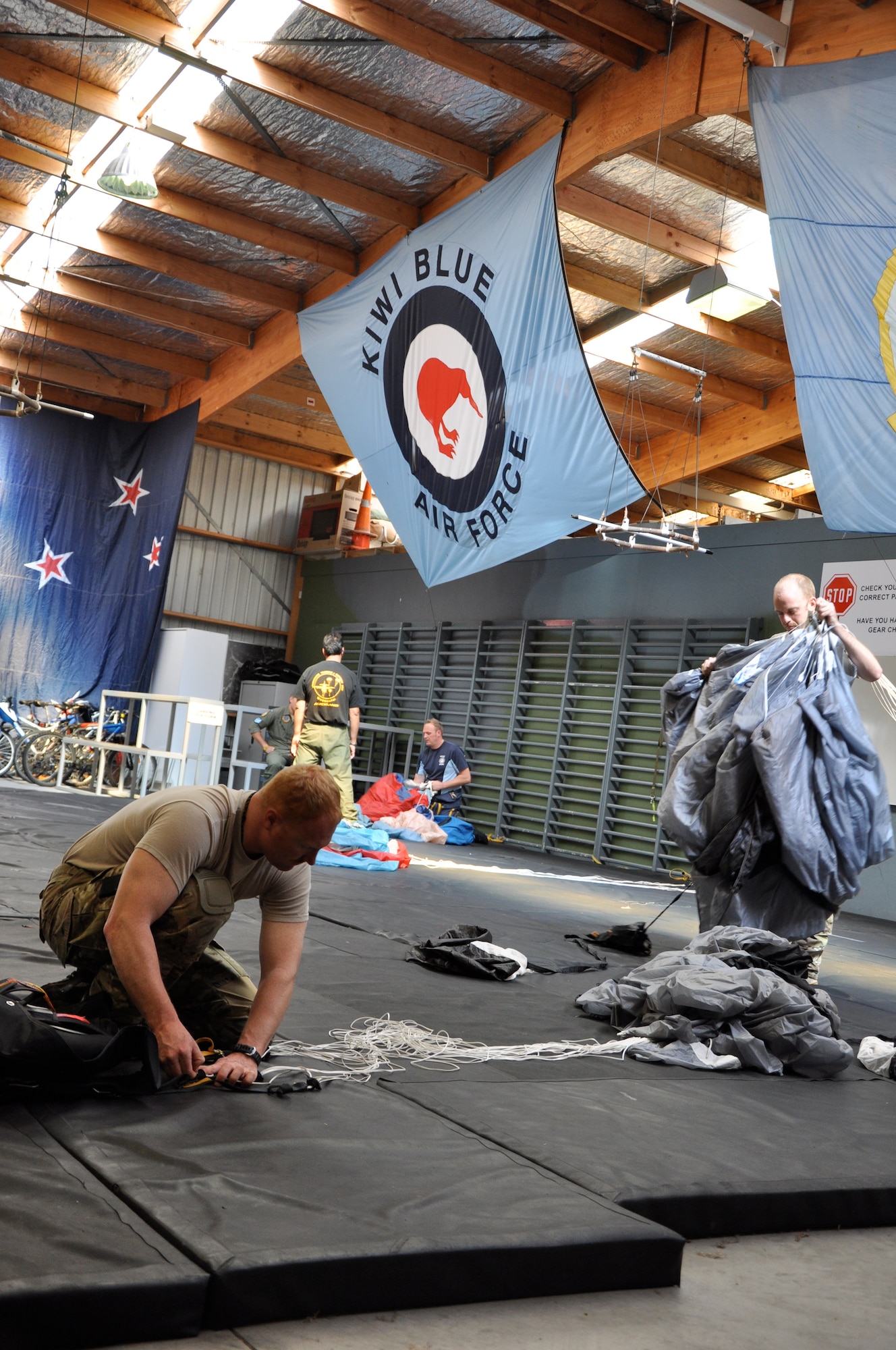 TSgt Jesse Stoda and TSgt Steven Raethel repack their parachutes after a jump with Airmen from the Royal New Zealand Air Force during Exercise Kiwi Flag. In addition to conducting airlift operations, jumpmasters from the USAF and RNZAF conducted subject matter expert exchanges, learning how each other accomplish parachute operations, increasing interoperability between the countries.  (U.S. Air Force photo by Capt. Rebecca Heyse/Released)