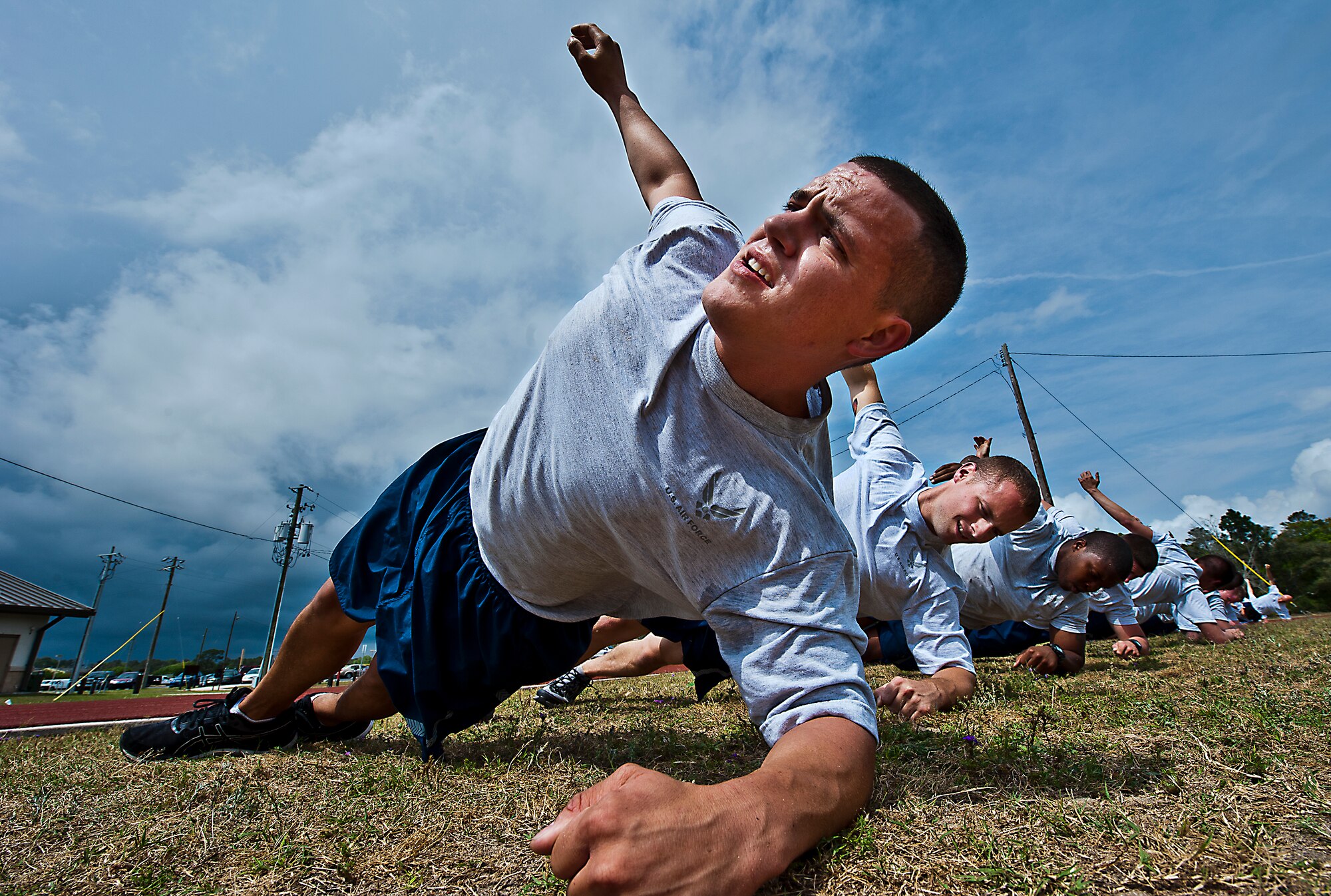 Staff Sgt. Bobby Brewer, 46th Maintenance Group, and more than 20 others perform a side bridge during a physical training leader class March 30 at Eglin Air Force Base, Fla.  PTLs lead their flights and squadrons in group PT sessions during the week throughout the base.  (U.S. Air Force photo/Samuel King Jr.)