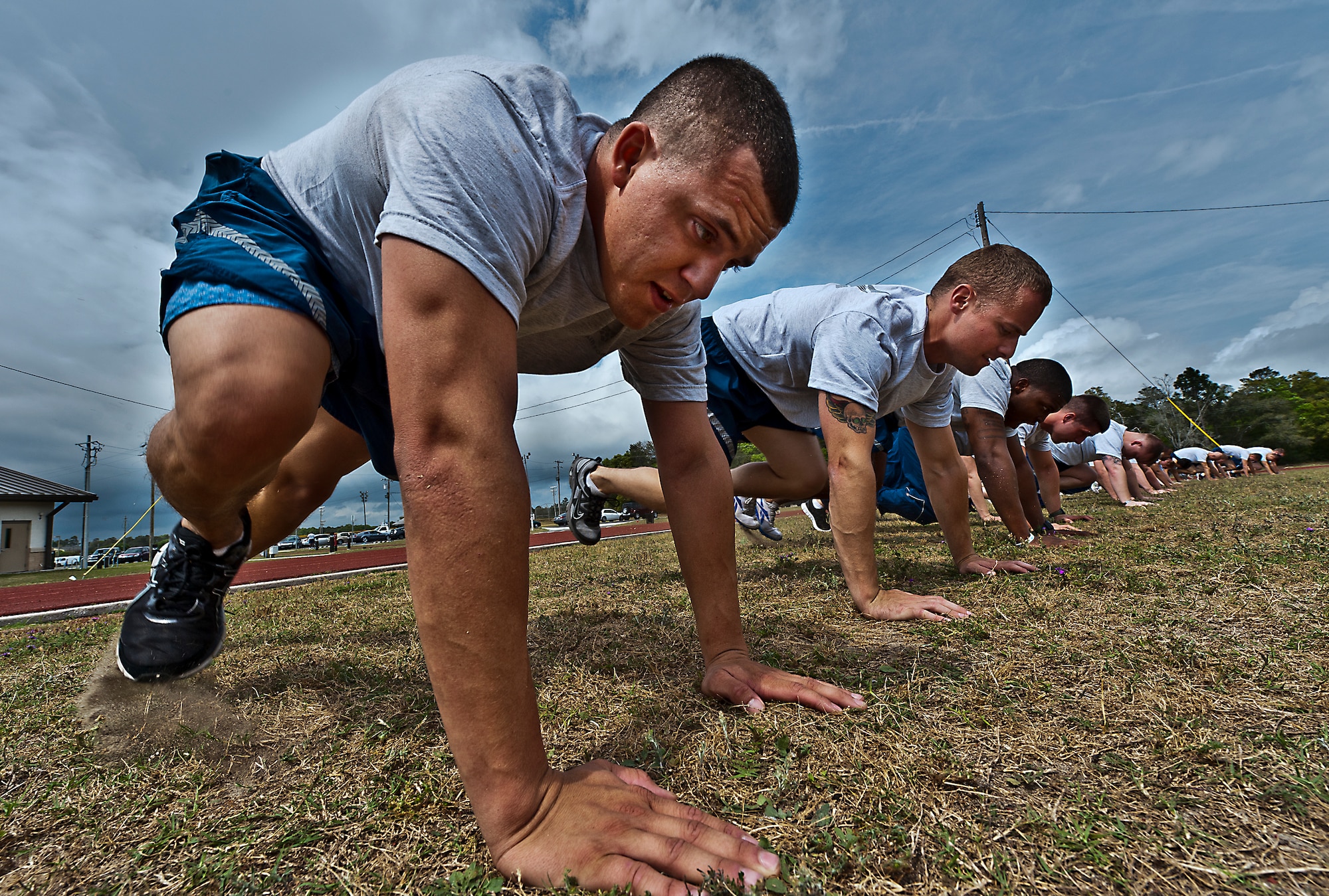 Staff Sgt. Bobby Brewer, of the 46th Maintenance Group, and more than 20 other Airmen perform “mountain climbers” during a physical training leader class March 30 at Eglin Air Force Base, Fla.  PTLs lead their flights and squadrons in group PT sessions during the week throughout the base.  (U.S. Air Force photo/Samuel King Jr.)