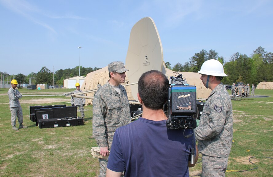Staff Sgt. Benjamin Holmes, 53rd Combat Communications Squadron Radio Frequency technician, briefs Reynolds Wolf, CNN meteorologist and correspondent, on the GMT (ground multi-band terminal) satellite system, a key component to extend and defend the network as Ferre Dollar documents the interview here March 28. A three-person CNN team visited the 689th Combat Communications Wing to experience what it is like to be a combat communications Airman for the day. Combat Comm provided hands-on experiences that showcased the physical, technical, and mental readiness of Combat Communicators.  (U.S. Air Force photo by Robert Talenti)