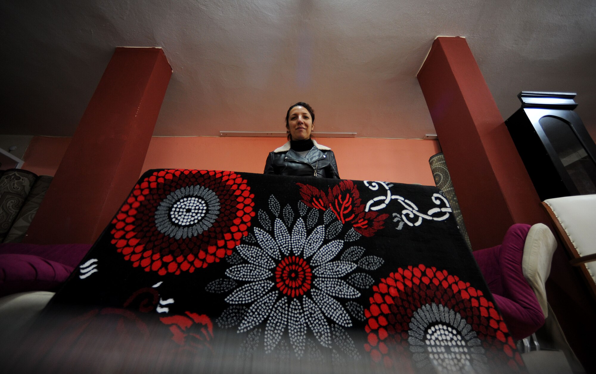 Arzu Ogun, Freedom Furniture owner, displays a carpet for a new customer March 29, 2012, in Incirlik Village, Turkey. Freedom Furniture is registered with the Incirlik Village Merchants Association, which was founded approximately 20 years ago with the objective to improve relationships with American customers. (U.S. Air Force photo by Senior Airman Jarvie Z. Wallace/Released) 