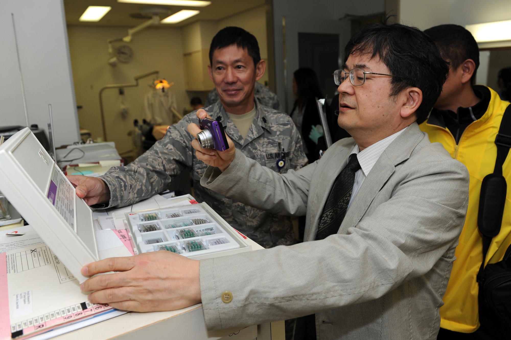 U.S. Air Force Lt. Col. Wataru Odomo, a dentist from the 18th Dental Squadron, holds dental supplies while Dr. Takahiko Tomoyose, from the Tomo Dental Clinic, takes a photo for future reference of his work at the Kadena Dental Clinic March 27. The 18th Dental Squadron hosted a half-day seminar with the invitation of the Kadena Air Base Okinawa Host Nation Dental Providers. The seminar kicked off with a mission brief greeting and a tour of the Dental Clinic facility. During the tour, host nation providers were able to exchange medical ideas and get information about the Kadena Dental Clinic system. (U.S. Air Force photo by Junko Kinjo/Released)

