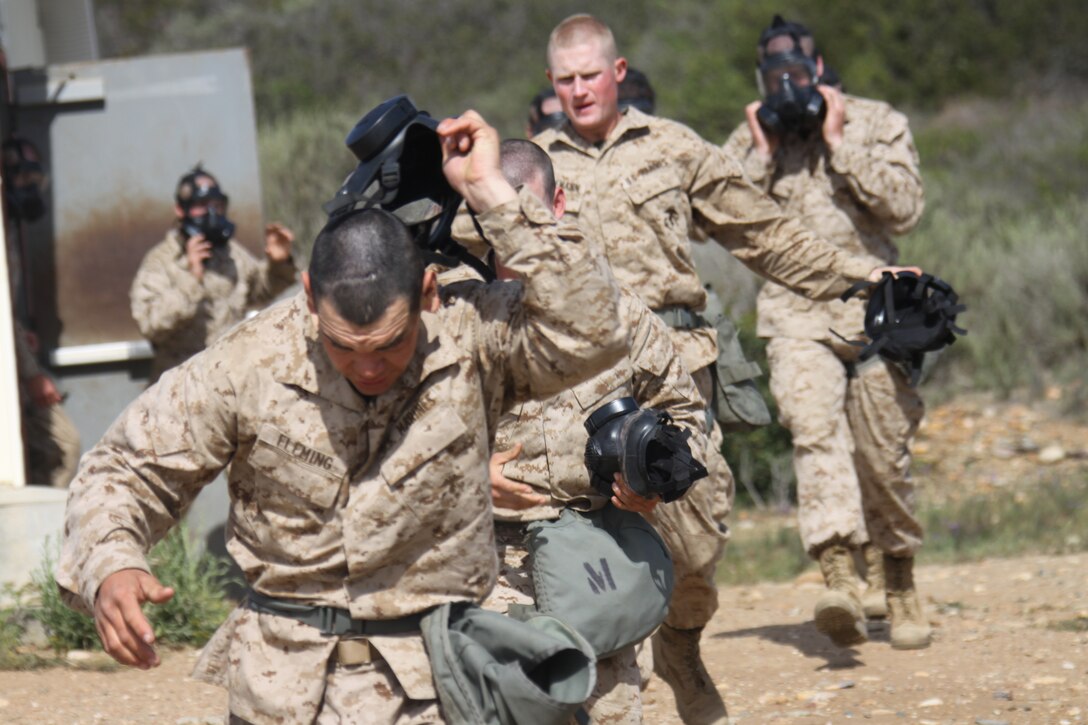 Company C recruits pull off their gas mask while running out of the Confidence Chamber April 2 aboard Edson Range, Marine Corps Base Camp Pendleton. Recruits were exposed to CS gas, a tear gas, that causes mucus discharge and burning of the skin.