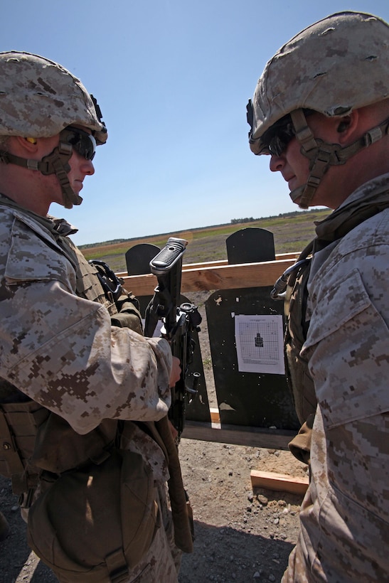 Private First Class Kyler R.Webbs (left) and Cpl. Joshua A Powell, combat engineers with Charlie Company, 2nd Combat Engineer Battalion, 2nd Marine Division, work together to improve Powell’s weapon accuracy prior to a live-fire exercise targeting unknown distance targets April 4. The training was part of required pre-deployment training for Afghanistan. Marines used M-4 service rifles and squad automatic weapons to fire approximately 80 rounds at green, pop-up targets