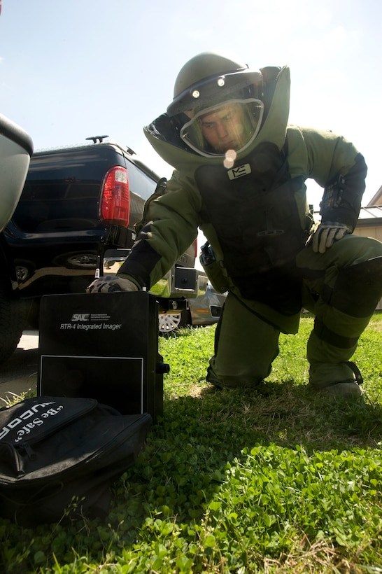 Senior Airman Brian Mink, an 11th Civil Engineer Squadron Explosive Ordnance Disposal technician, wearing an EOD-9 bomb suit, places an RTR-4 Integrated Imager near a suspicious package during Improvised Explosive Device training here March 29. (Photo/Bobby Jones)