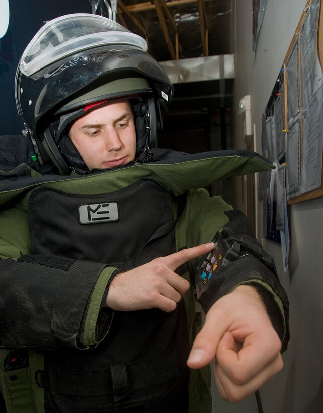 Senior Airman Brian Mink, 11th Civil Engineer Squadron Explosive Ordnance Disposal technician, keys in commands on his EOD-9 bomb suit during an Improvised Explosive Device training mission March 29. EOD techs use the key pad on the suit to control the climate inside the suit and to communicate with other EOD techs. (Photo/Bobby Jones)