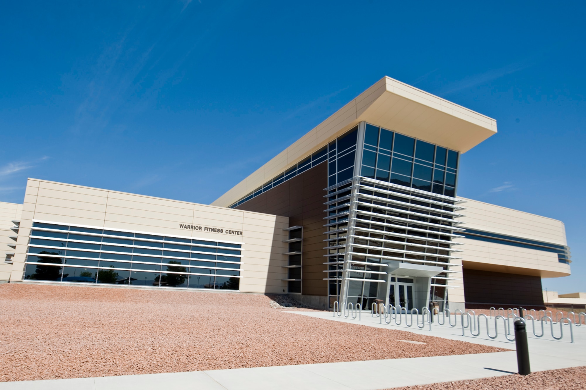 The exterior of Warrior Fitness Center March 30, 2012, at Nellis Air Force Base, Nev. The state-of-the-art fitness center offers three racketball, three basketball and three volleyball courts, an indoor swimming pool and a variety of cardio and weight training equipment.  (U.S. Air Force photo by Lawrence Crespo)
