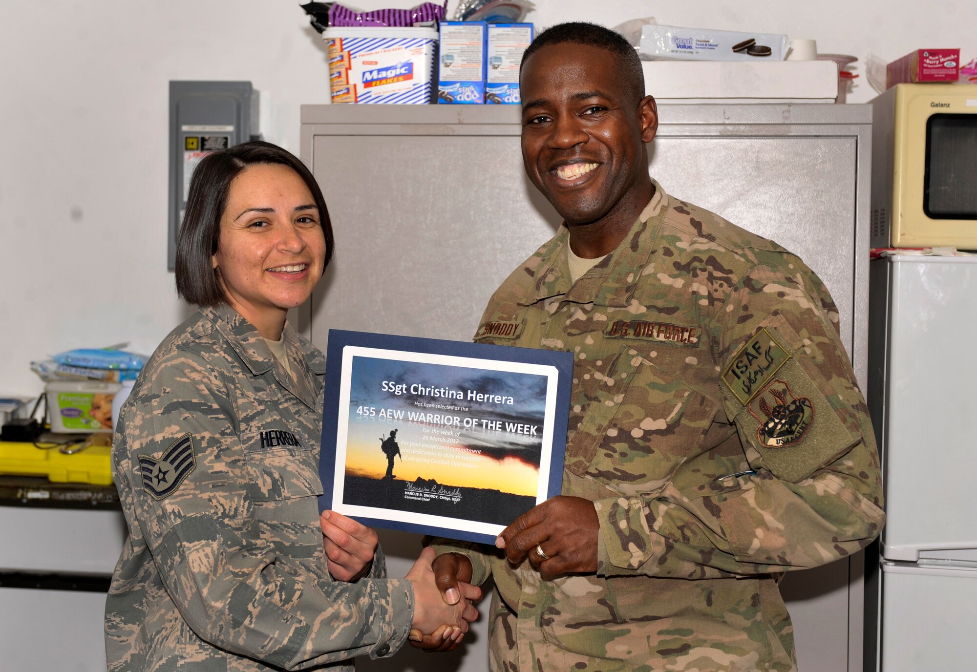 BAGRAM AIRFIELD, Afghanistan— Staff Sgt. Christina Herrera receives the Warrior of the Week award from 455th Air Expeditionary Wing Command Chief Chief Master Sgt. Marcus Snoddy at Bagram Airfield, Afghanistan, April 3, 2012. Herrera is noncommissioned officer in charge of the Medical Information Systems Help Desk with the 455th Expeditionary Medical Support Squadron and earned the Warrior of the Week award for her hard work and dedication to excellence. (U.S. Air Force photo/Airman 1st Class Ericka Engblom)