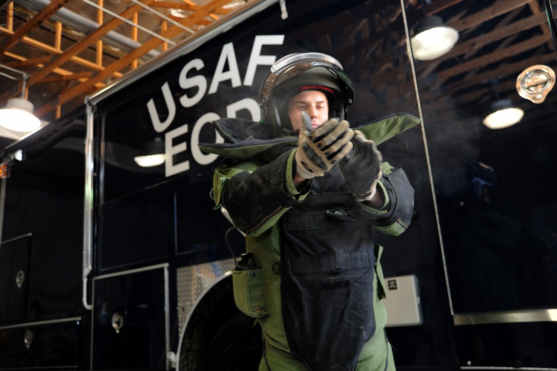 Senior Airman Brian Mink, an 11th Civil Engineer Squadron Explosive Ordnance Disposal technician, dusts off his gloves after donning his EOD-9 bomb suit prior to Improvised Explosive Device training March 29. (U.S. Air Force Photo/Staff Sgt. Matt Coleman-Foster)